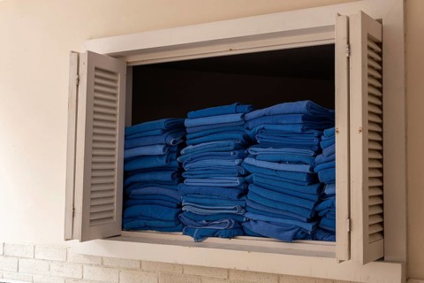 A window displays neatly stacked blue towels in a hotel setting in Turkiye. The towels are folded