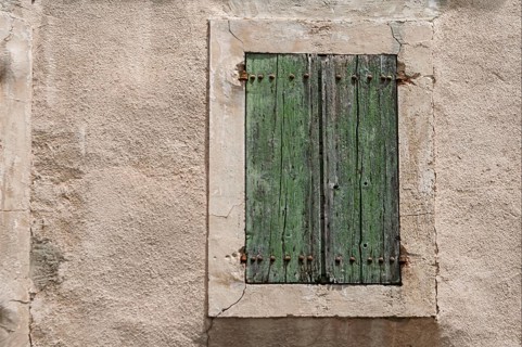 Weathered green wooden shutters in front of an old, rough wall, Provence, France