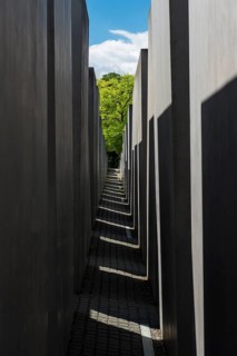 Light and shadow in the corridor of the memorial to the murdered Jews with a view of a green tree,