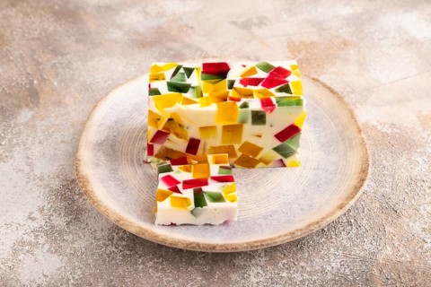 Colored Fruit and milk jelly on brown concrete background, side view, close up, minimalism