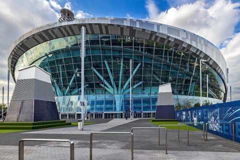Sunlight catches the curved glass and steel facade of Tottenham Hotspur Stadium on White Hart Lane,