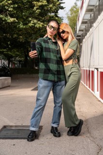 A Colombian lesbian couple captures a selfie, embracing in an urban environment, reflecting love,