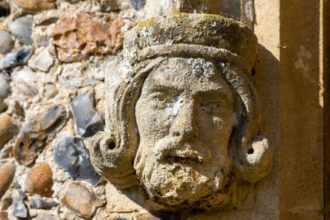 Weathered medieval carved stonework head of a king, church of Saint Peter, Theberton, Suffolk,