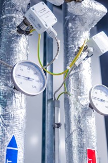 Silver pipes with pressure gauges and temperature indicators in a technical environment,