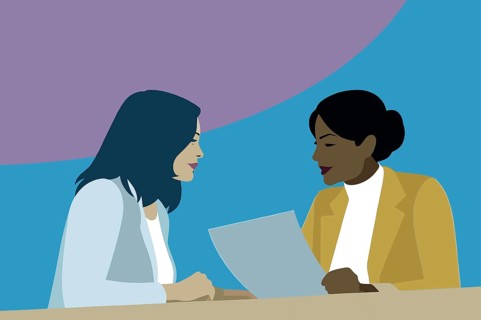 Two women engage in a business discussion, reviewing a document together at a table, with a vibrant