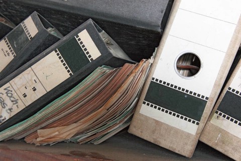 Office scene around 1982, lost place, abandoned location, classic file folders on a wooden shelf,