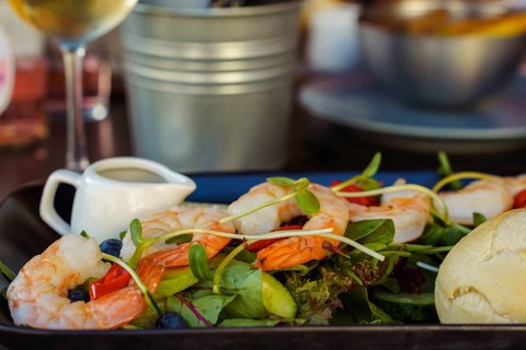 Shrimp salad on a table in a restaurant close-up. Healthy food, Fresh shrimp salad with greens and