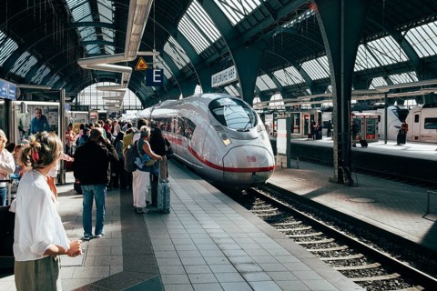 Modern ICE 3 on a platform in the midst of travelers under the characteristic rail hall, station