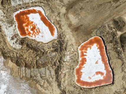 Saline ponds with ruddy algae growth and white salt deposits at the Skeleton Coast. Aerial view.
