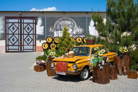 Yellow car decorated with flowers and wooden decorations on a paved square, vintage car,