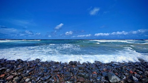 Wide view of the sea with stones, waves under blue sky, Sao Vicente, Cabo Verde, Cape Verde