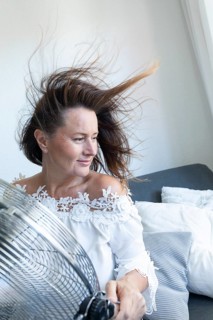 Woman relaxing in front of an electric fan during hot weather at home