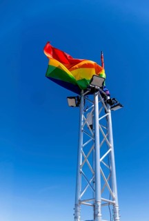 Rainbow flag on a technical truss tower on which LED spotlights are mounted, Berlin, Germany