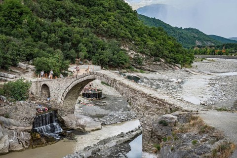 BENJA, ALBANIA - JULY 1, 2026: Historic Ottoman stone arch bridge spanning over a river in a rocky