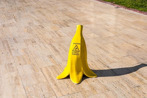 A yellow banana-shaped caution sign stands by a swimming pool. The pool is surrounded by modern