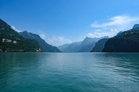 View of Lake Lucerne surrounded by mountains under a clear blue sky, fountain, Canton of Schwyz,