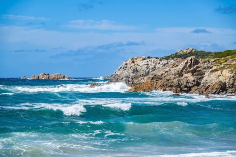 Coastline with emerald green and blue water on a sunny day at Rena Majori beach, Sardinia, Italy