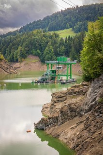 Green technical plant stands on calm water, surrounded by slightly cloudy hills, Krumbach,