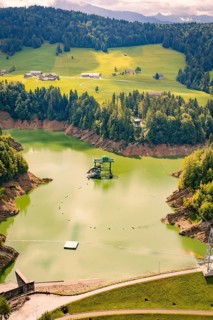 Green lake nestled in a hilly landscape, surrounded by trees, Krumbach, Vorarlberg, Austria