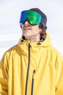 A man in a vibrant yellow snow jacket and futuristic goggles enjoys a sunny winter day on the