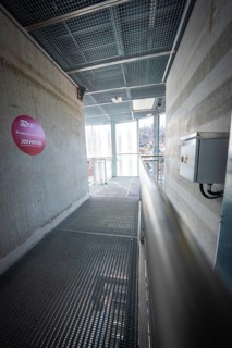 Modern corridor with grid floor and concrete walls, industrial atmosphere, Hermann Hesse Bahn, ZOB,