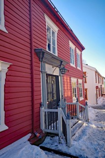 Red wooden houses along a snow-covered path under a clear sky, Røros, mining town, Unesco World