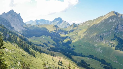 Scenic panorama of the Jaun Pass in the Swiss Alps, featuring verdant mountains and clear skies