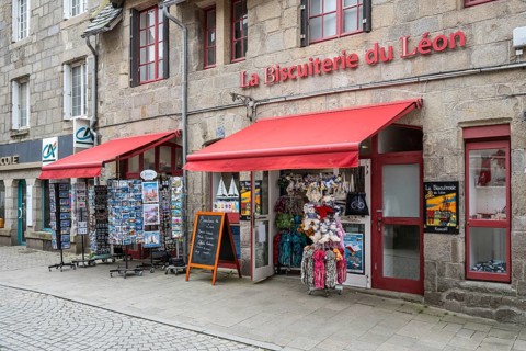 A typical Breton biscuiterie, souvenir shop with red canopy and postcard stands in front of the