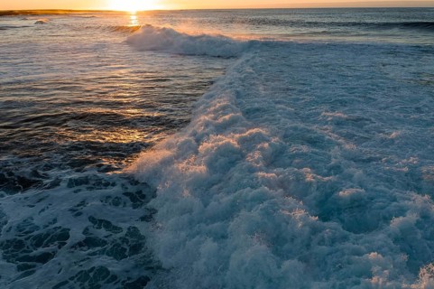Waves crash energetically at Popcorn Beach in Fuerteventura during a picturesque sunset, creating a