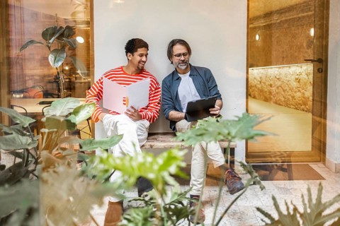 Two professionals enjoy a relaxed outdoor meeting in a modern coworking space surrounded by lush