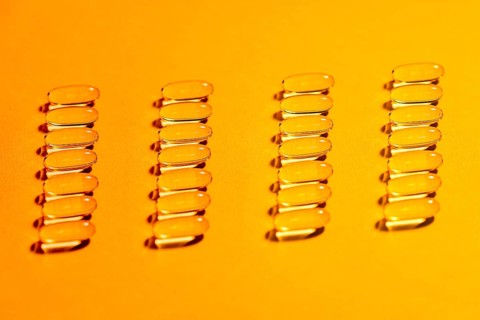 The image showcases multiple rows of clear, oval shaped capsules meticulously arranged on a