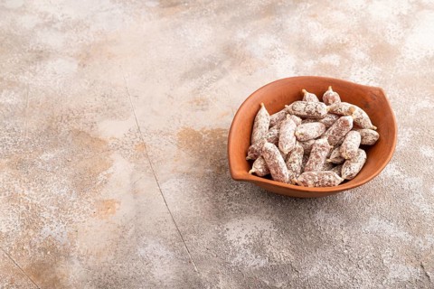 Small smoked Chicken sausages in clay bowl on brown concrete background. side view, copy space