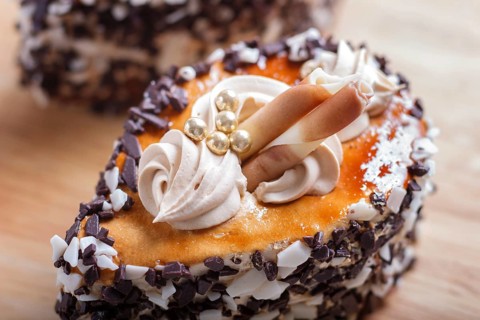 Cakes with chocolate chips and cream decorations on wooden board on white background. selective