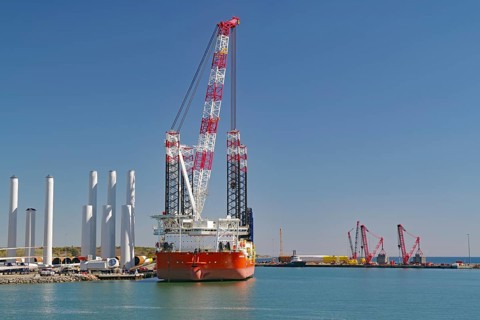 A large crane in the harbor with several ships and clear blue sky in the background, Windkraft,