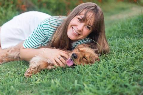 Affectionate moment in the grass as a woman smiles at her dog Cocker Spaniel