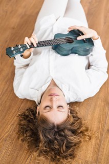Person lying on the floor with a ukulele, exuding a sense of calmness