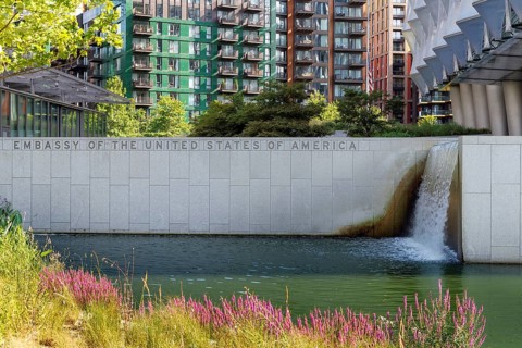 Water cascades down a stone wall inscribed Embassy of the United States of America beside a