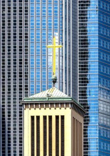 Church tower with the cross of the Protestant St. Matthew Church in front of the glass façade of an