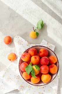 Fresh apricots in a bowl, on a bright table, natural light, top view, no people