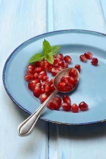 Pomegranate seeds and spoons on plate, Punica granatum