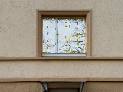 Window of a house façade that is completely covered from the inside with aluminum foil — improvised