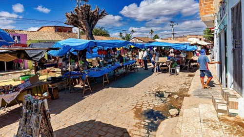 Market stalls under blue skies on a paved street with local natives, market scene in a small town