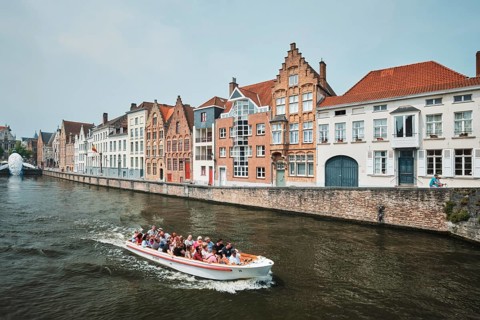 BRUGES, BELGIUM, MAY 29, 2018: Tourist boat in canal between old houses with The Bruges Whale