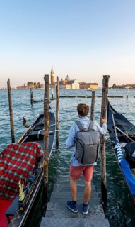 Young man at a boat dock for Venetian gondolas in St. Mark's Square, tourist enjoying the evening,