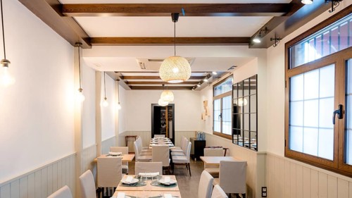 A modern restaurant interior with elegant decor. Wooden beams complement white walls, while soft