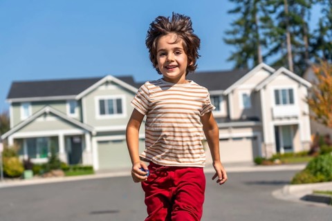 Young boy enjoying childhood, running and smiling towards the camera on a sunny day in a peaceful,