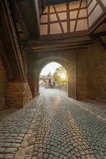 20 August 2026, Sunlight shines through the historic archway of the medieval town gate in Iphofen,