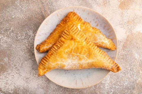 Triangles Pie, Puff Pastry, Samsa with cherry jam on brown concrete background, top view, flat lay,