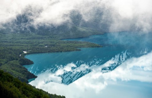 View of snowy mountains in spring and turquoise Kenai Lake with reflection, Slaughter Ridge Trail,