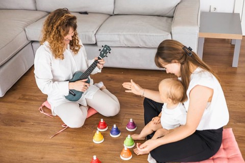 A joyful scene with a woman playing ukulele and a baby surrounded by colorful bells
